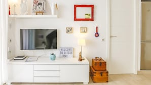 Een moderne woonkamer met een witte tv-meubel, een flatscreen televisie en een gastvrij bord.