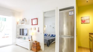 Een moderne, goed verlichte kamer met een bed, een televisie, een bureau en een kledingkast.