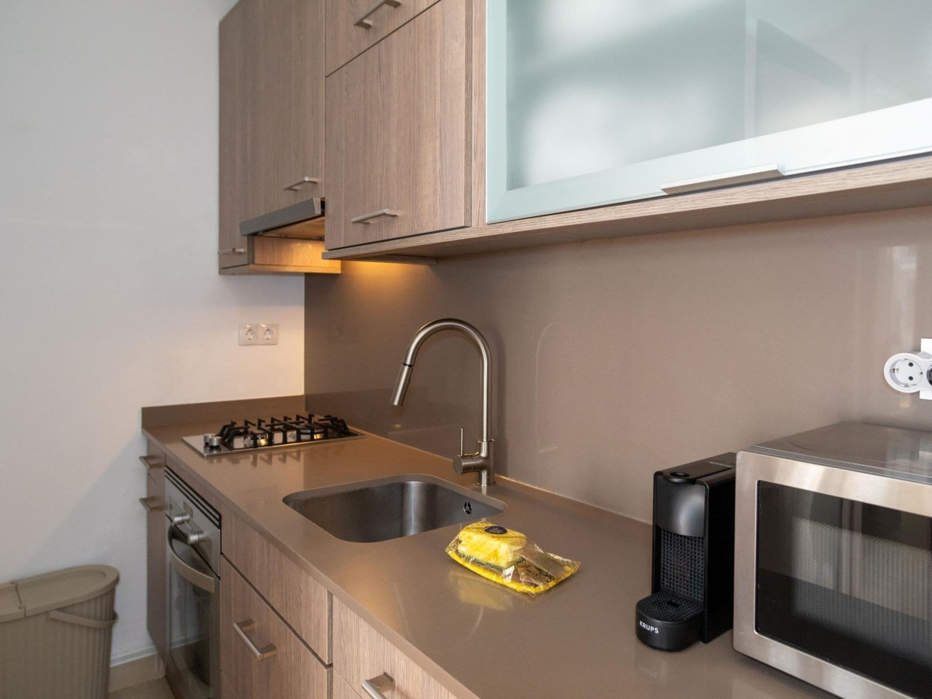 A modern kitchen with a double sink, stainless steel appliances, and wooden cabinetry.