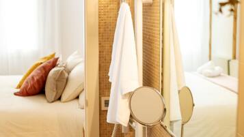 Un baño de hotel con ducha, un espejo y una cama con almohadas.