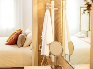 Un baño de hotel con ducha, un espejo y una cama con almohadas.