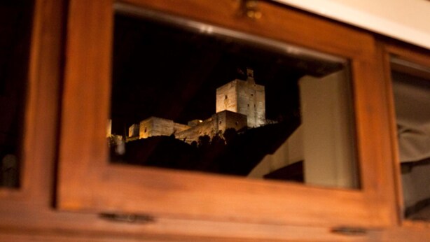 A wooden-framed window with a view of a castle-like structure at night. - Apartamento Amanecer en Granada (Granada)