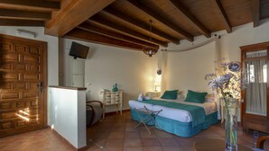 A bedroom with a bed, a bedside table, a chair, a wooden ceiling, a wall-mounted TV, and a window with curtains. - Apartamento Terraza Albaicin (Granada)
