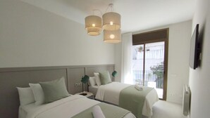 Habitación de hotel con dos camas, un balcón y una lámpara de araña moderna.