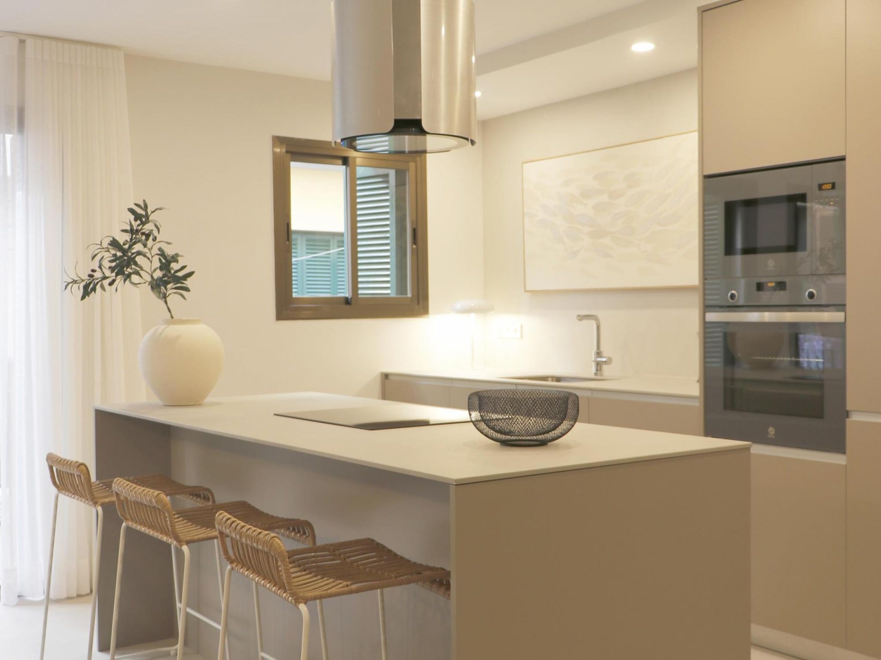 Una cocina moderna con una isla central, taburetes de bar, un lavamanos y electrodomésticos empotrados.