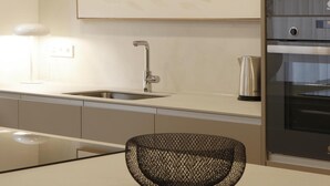 Una cocina moderna con un lavamanos de acero inoxidable, un hervidor y un horno empotrado.