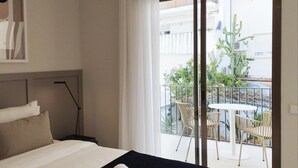 Una habitación de hotel con una cama, vista al balcón y mobiliario exterior.