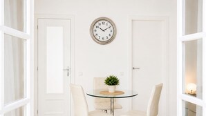 A room with a round glass table, two white chairs, a clock on the wall, and a door. - Apartamnet en el Centro de Sitges con Terraza (Sitges)