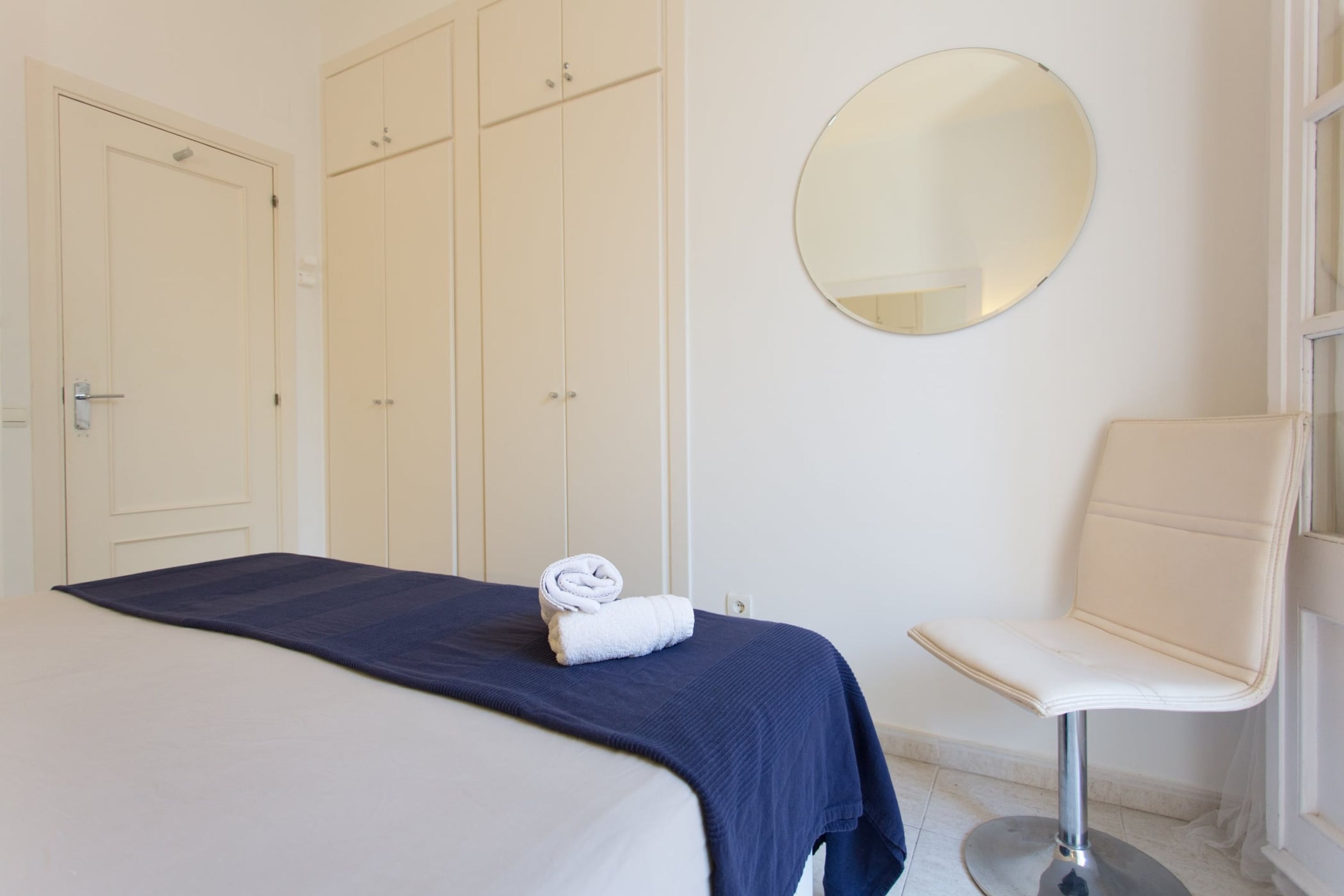 Une chambre d’hôtel avec un lit, une chaise, une armoire et un miroir.