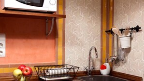 Uma cozinha com micro-ondas, pia e uma fruteira.
