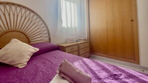 A bedroom with a bed, a wooden headboard, a nightstand, a dresser, and a wardrobe. - Rental Unit in Calafell 3 Bedrooms 3 Beds 1 (El Vendrell)