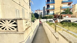 A narrow concrete pathway flanked by buildings with balconies and a railing. - Rental Unit in Calafell 3 Bedrooms 3 Beds 1 (El Vendrell)