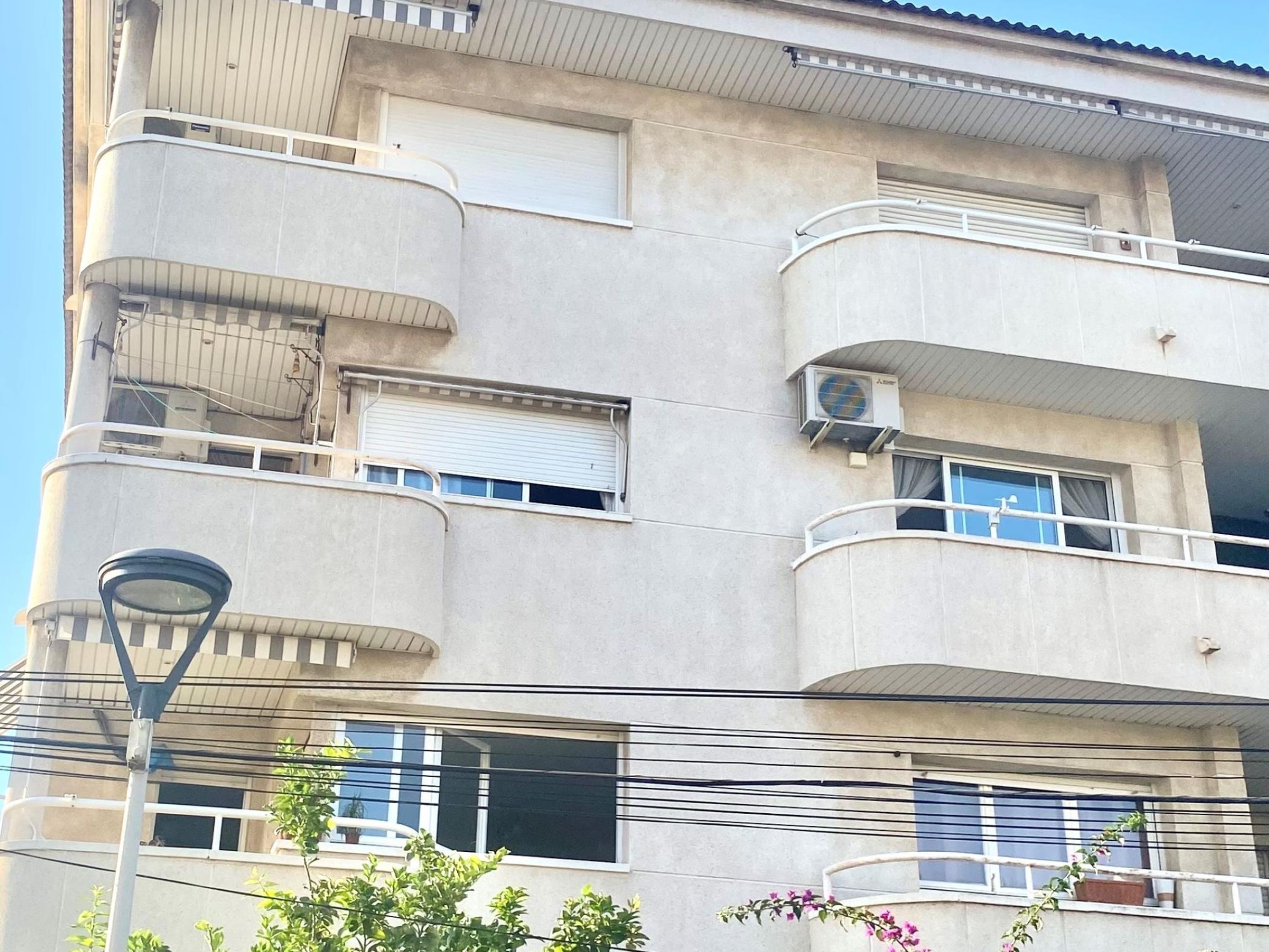 Un immeuble à plusieurs étages doté de balcons, de climatiseurs et d’un lampadaire.