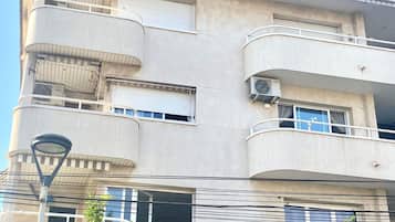 Un immeuble à plusieurs étages doté de balcons, de climatiseurs et d’un lampadaire.
