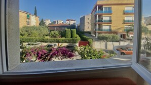A view from a window of a residential area with buildings, cars, and flowering plants. - Rental Unit in Calafell 3 Bedrooms 3 Beds 1 (El Vendrell)