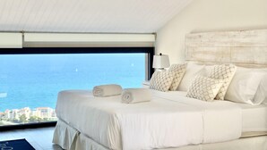 A bedroom with a large bed, a view of the sea, and a wooden ceiling. - Sitges Spaces Sea View Villa (Sitges)