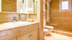 A modern bathroom with a marble countertop, a sink, a mirror, a toilet, and a shower area. - Casa Independiente con Jard n y Piscina Privada (Sant Pere de Ribes)