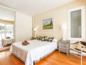 A bedroom with a bed, two bedside tables, a chair, a large window, and a painting on the wall. - Casa Independiente con Jard n y Piscina Privada (Sant Pere de Ribes)