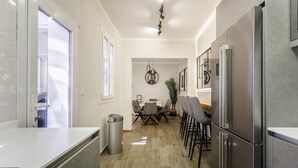 Una cocina moderna con una isla central, electrodomésticos de acero inoxidable y un comedor con candelabro.