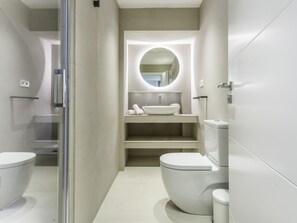 Une salle de bain moderne dotée d’une douche à parois de verre, de toilettes sur pied et d’un meuble-lavabo avec un évier et un miroir.