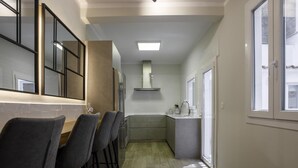 Una cocina moderna con una isla central, taburetes de bar y un ventanal que proporciona luz natural.