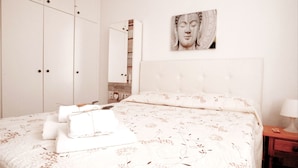 A bedroom with a large bed, a wardrobe, a mirror, and a wall-mounted artwork. - C Ntrico y a pie de Playa en los Cristianos (Arona)