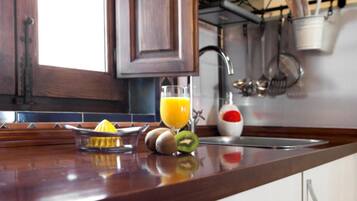 Una encimera de cocina con un extractor de zumo, un vaso de zumo de naranja y un kiwi.