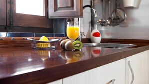 A kitchen counter with a juicer, a glass of orange juice, and a kiwi. - Apartamento Rio Genil (Granada)