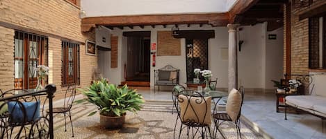 Une cour avec un sol carrelé, des sièges extérieurs et une plante en pot.