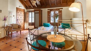 A room with a bed, a round glass table, a chair, a lamp, and a door. - Apartamento Rio Genil (Granada)
