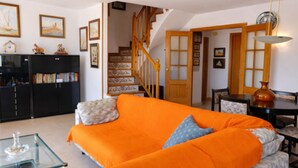 A living room with a sofa, a glass coffee table, a staircase, and a dining area. - Duplex con Zona Comunitaria Ideal Familias Coral (Sitges)