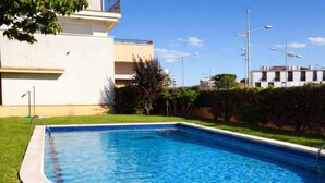 A rectangular swimming pool with a white edge, surrounded by a grassy area and a hedge. - Duplex con Zona Comunitaria Ideal Familias Coral (Sitges)