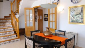 A dining area with a table, chairs, a vase, and a staircase. - Duplex con Zona Comunitaria Ideal Familias Coral (Sitges)