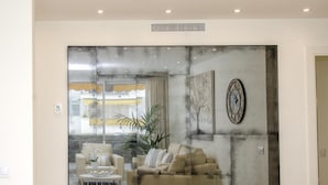 A living room with a large abstract painting, a sofa, a coffee table, and a potted plant. - Sitges Spaces Oasis Suites (Sitges)