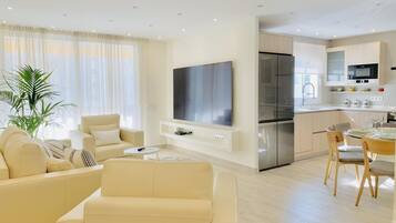 Una sala de estar moderna con sofá, televisor y zona de comedor con sillas y una mesa.