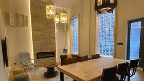 A spacious dining area with a large wooden table and multiple chairs, a stone wall, and a fireplace. - Cornelia Suites 03 in Santander (Santander)