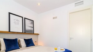 A neatly arranged bedroom with a bed, pillows, a framed quote, and a breakfast tray. - Sitges Spaces Sea View Oasis (Sitges)