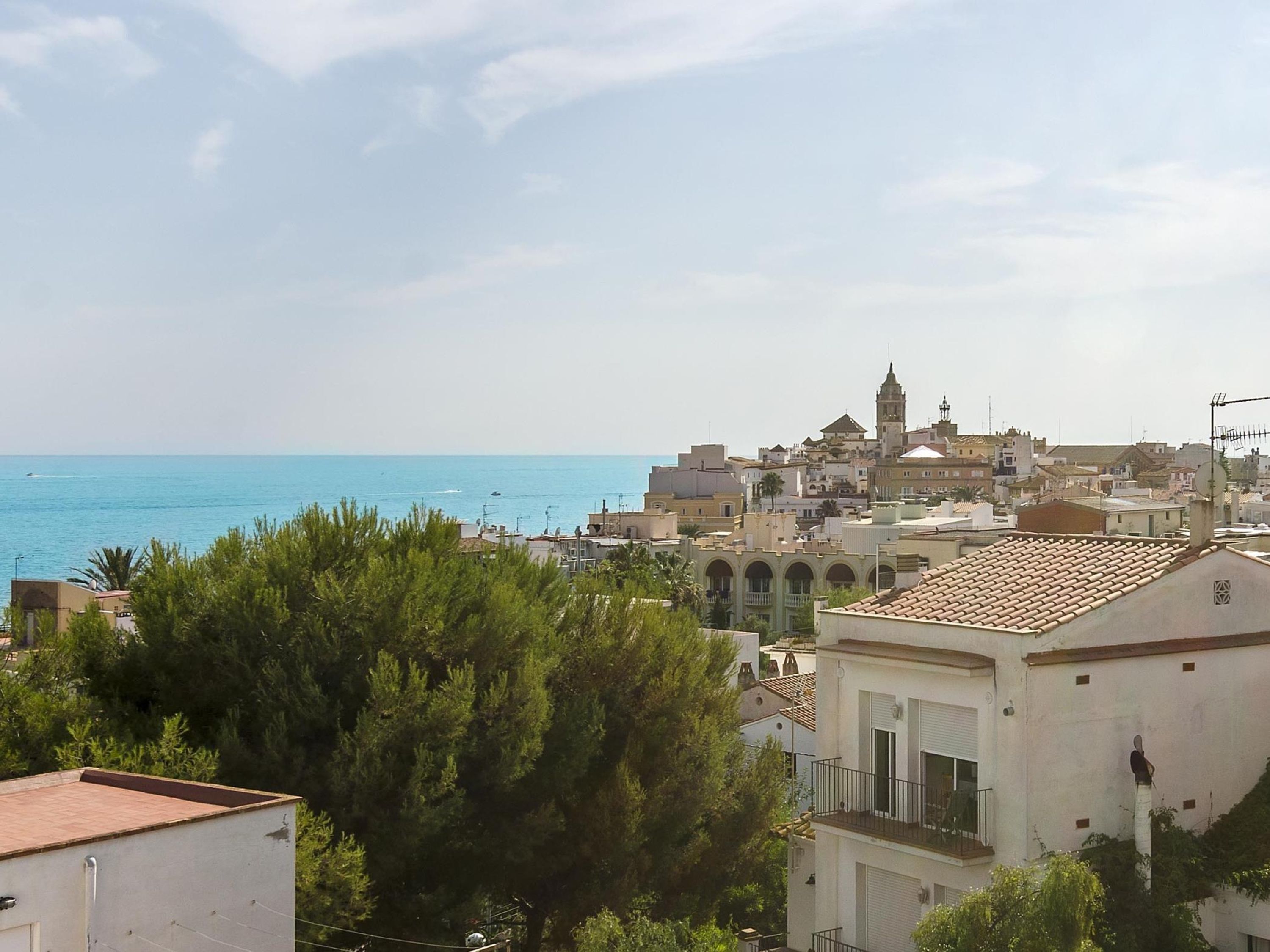 A coastal town with a prominent tower, terracotta-roofed buildings, and a view of the sea.