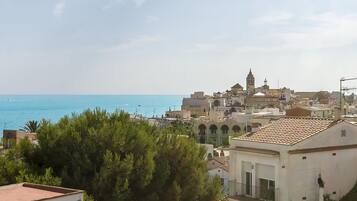 A coastal town with a prominent tower, terracotta-roofed buildings, and a view of the sea.