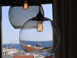 A clear view of the sea through a window with a hanging light fixture. - Sitges Spaces Sea View Oasis (Sitges)