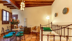 Una habitación acogedora con una cama, una mesa de comedor con sillas y una mesita con un jarrón de flores.