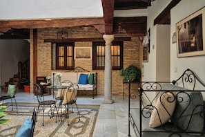 An outdoor seating area with a stone wall, a wooden ceiling, and a metal table and chairs.