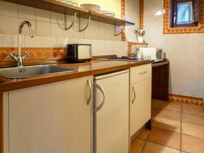 A kitchen with a sink, a microwave, a toaster, and a small window with curtains.