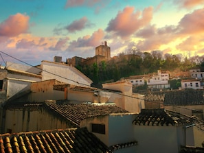 A historic town with traditional architecture, including a prominent castle on a hill and terracotta-tiled rooftops.