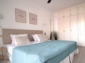 A neatly made bed with a teal bedspread, a wooden headboard, and two framed signs on the wall. - 21 Relax Oasis del mar (Santiago del Teide)