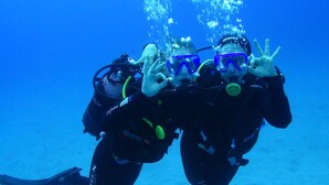 Two scuba divers underwater with their gear, including tanks and masks, and bubbles rising from them.