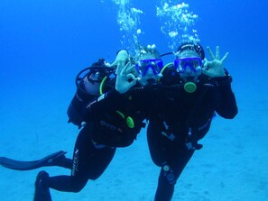 Deux plongeurs sous-marins, équipés de leurs appareils, notamment des bouteilles d’air et des masques, et des bulles qui s’élèvent autour d’eux.
