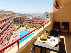 Un balcó amb piscina, gandules i una taula amb un barret i ulleres de sol.