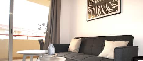 Una sala de estar moderna con un sofá gris, una mesita redonda y un jarrón decorativo.