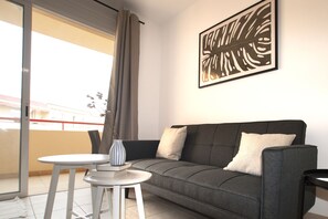 Un saló modern amb un sofà gris, una taula rodona petita i un ram de flors decoratiu.